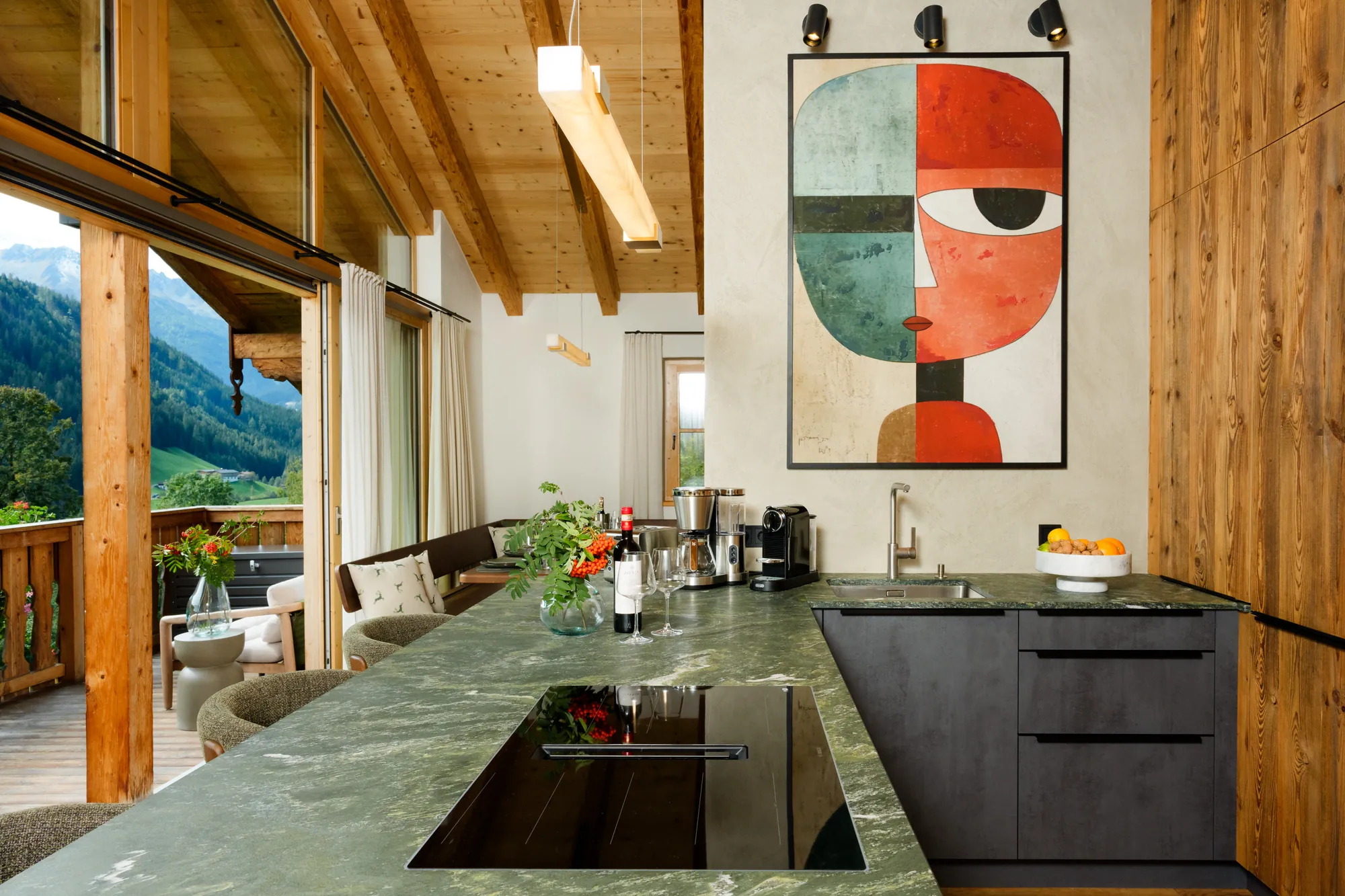 Kitchen counter with hob, green stone worktop and a view through the glass door to balcony and mountains
