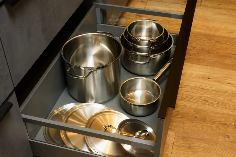 Kitchen drawer with stainless-steel cooking pots in various sizes and lids