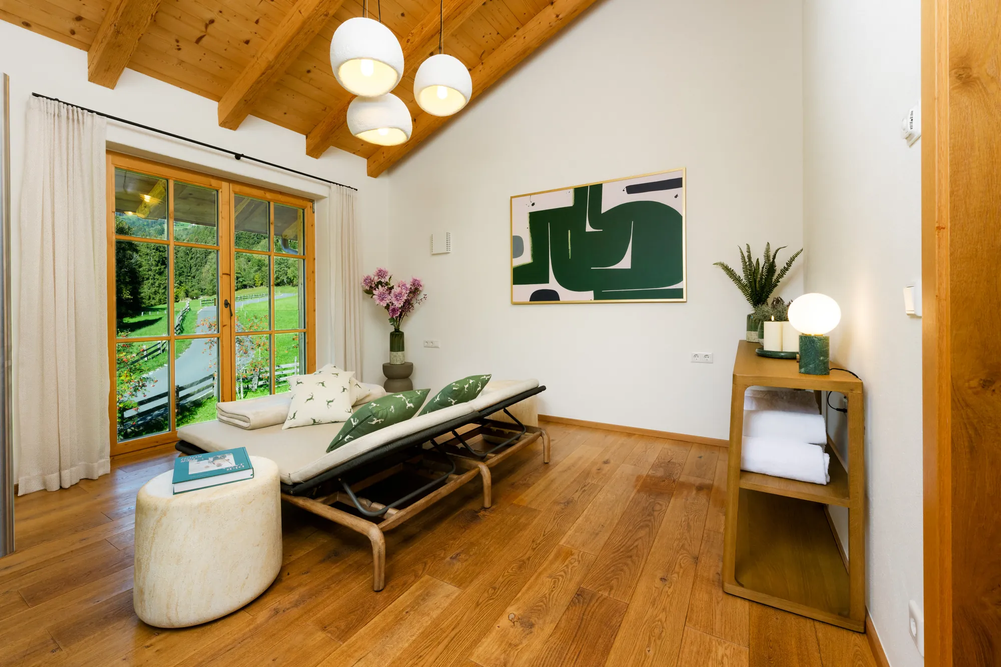 Relaxation room with two loungers, cushions with a deer motif, towel shelf, plants and a French window to the garden