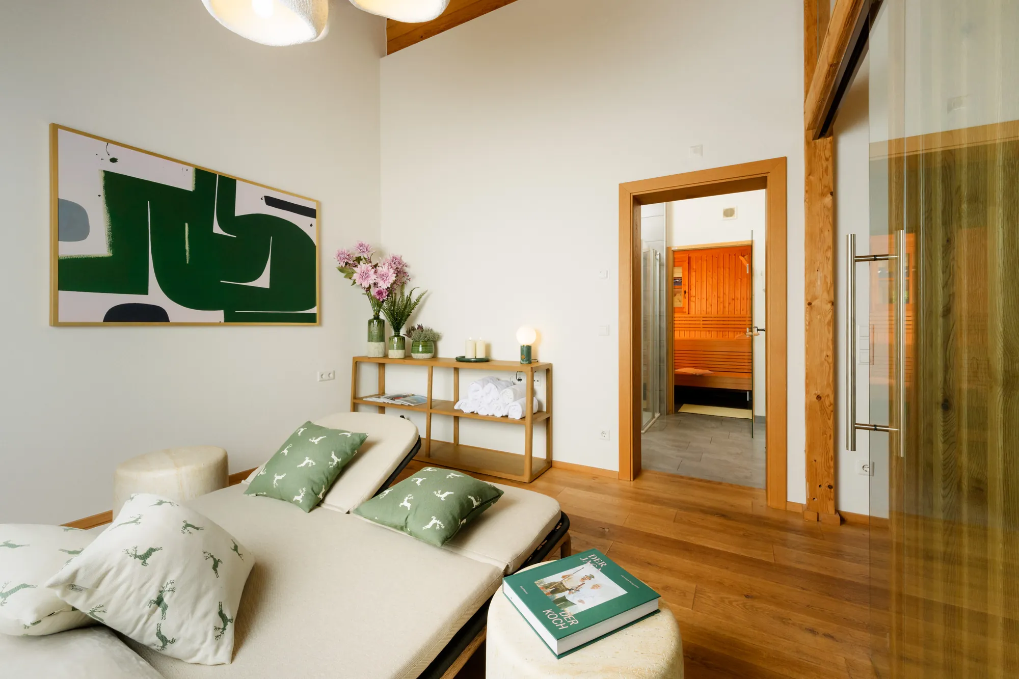 Relaxation room with loungers and deer cushions, the open door to the sauna and a towel shelf in the background