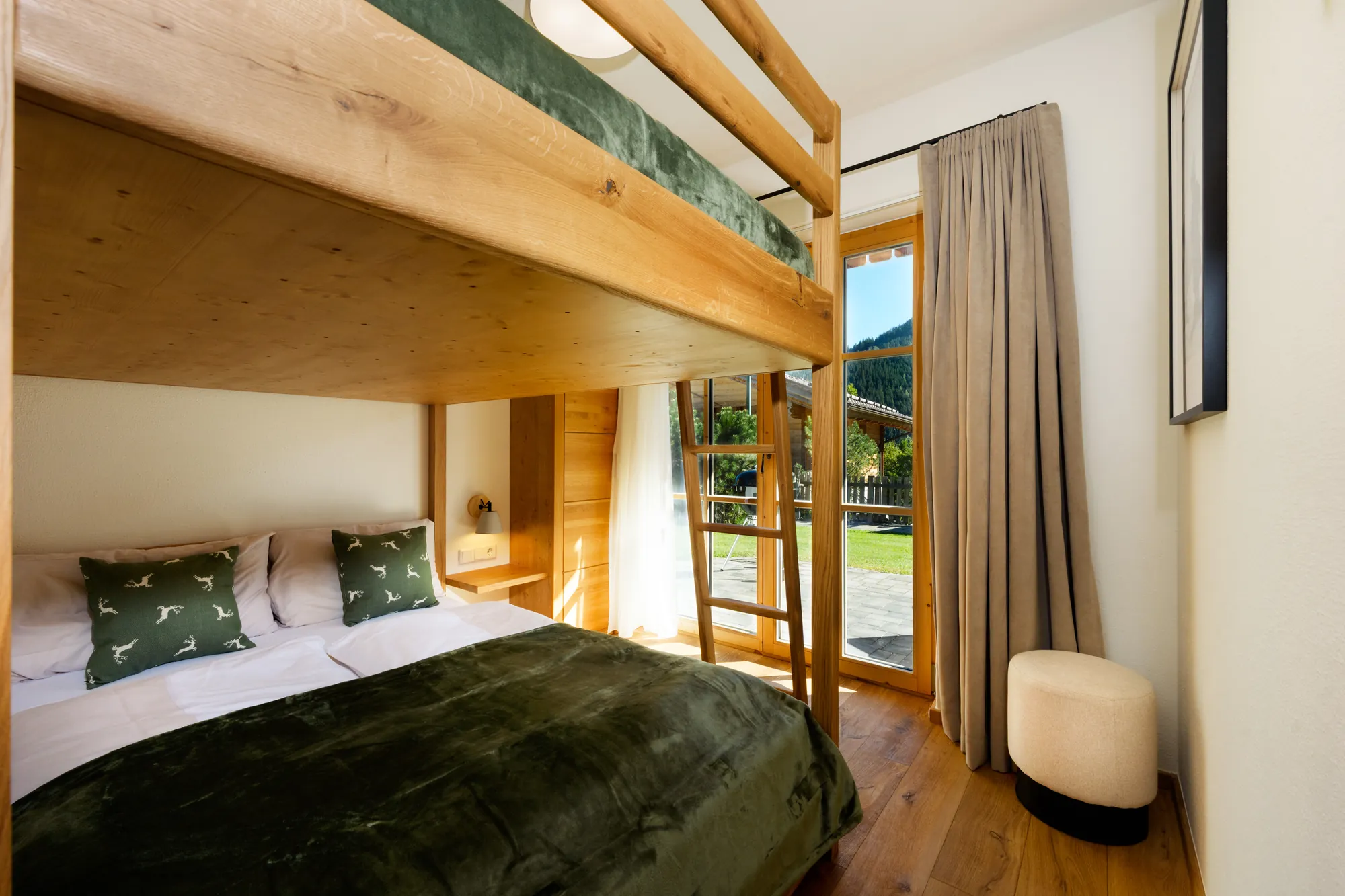 Wooden bunk bed with two 140 cm wide sleeping levels, green bedding and a French window to the greenery