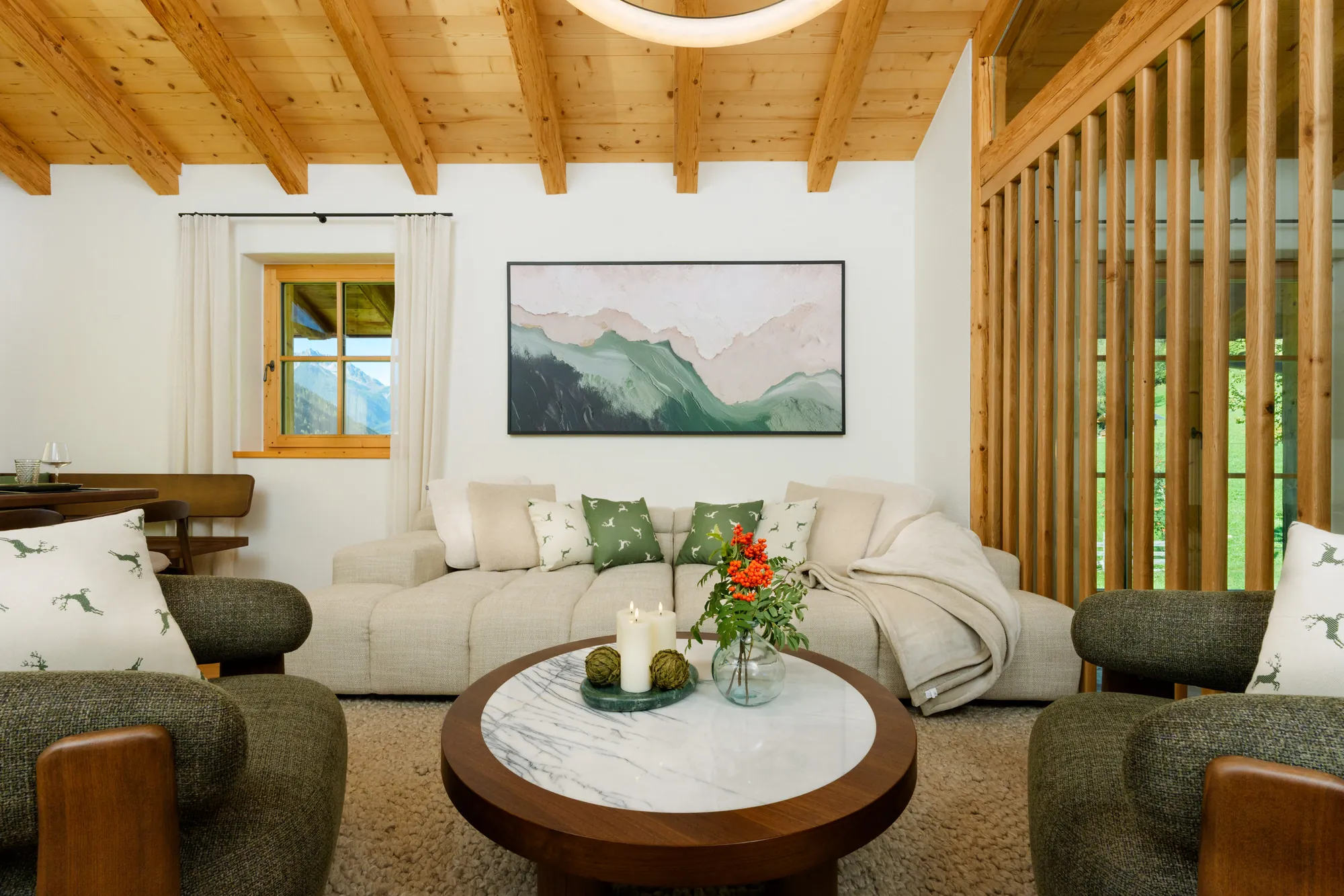 Living room with light sofa, two green armchairs, round marble coffee table and wooden ceiling